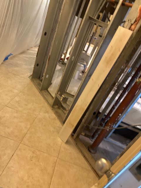 Rusted, mold-stained wall stud, and a cleaned stud wall with a bare tile floor.
