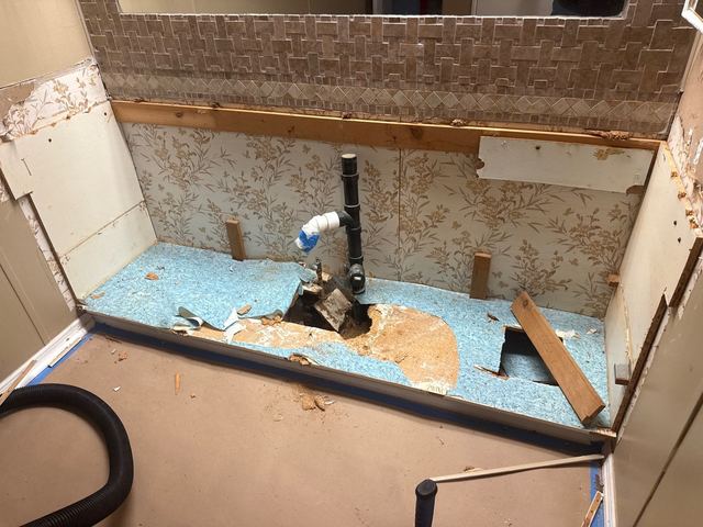 Bathroom vanity area opened to wet subfloor, and the protected floor with an air mover.